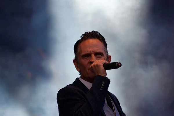 Man in suit and tie singing, smoke in background
