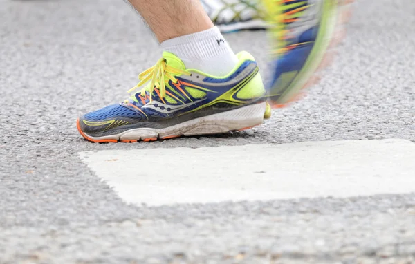 Close up of the blue and yellow shoes of a male runner