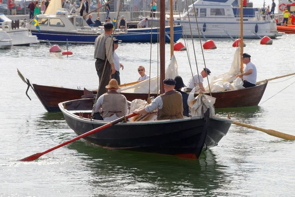 Sailors in vintage clothes rowing old sailing ships in the harbo