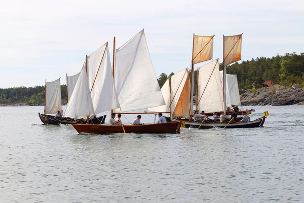 Group of small, old sailing ships rowing rapidly