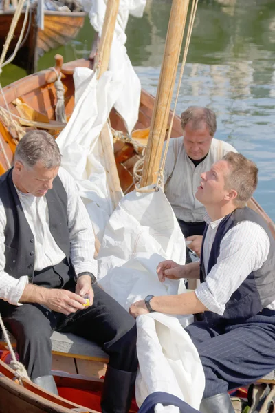 Sailors in vintage clothes preparing old sailing ships