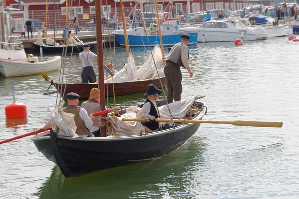 Sailors in vintage clothes using the oars old sailing ship