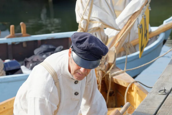 Old male sailor in vintage clothes preparing old sailing ship