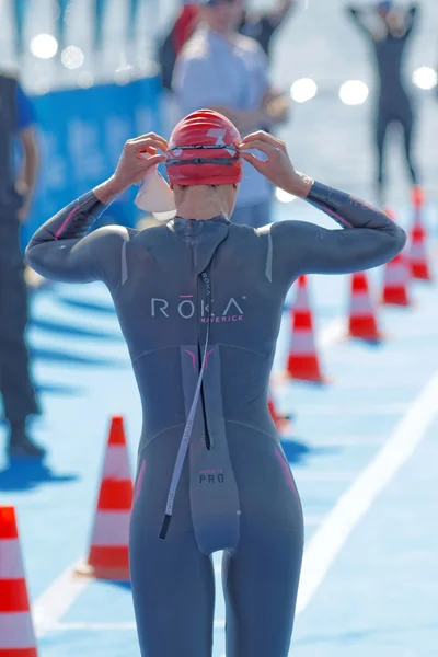 Rear view of female swimmer fixing the glasses