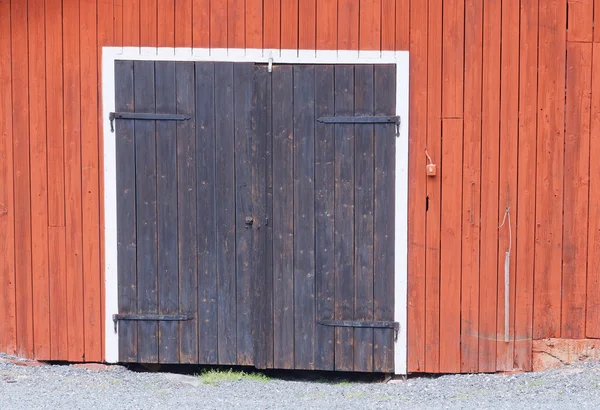 One black door in a red barn wall