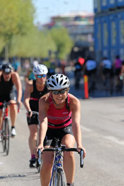 Smiling, cycling woman wearing pink tank-top followed by competi