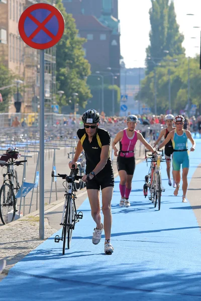 Men and woman running with bicycles in the triathlon transition