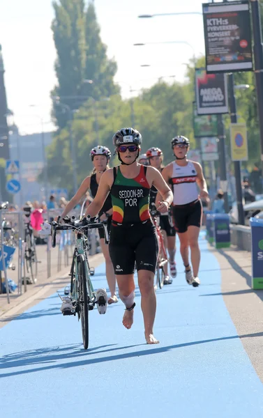 Many woman running barefoot with bicycle in the triathlon transi
