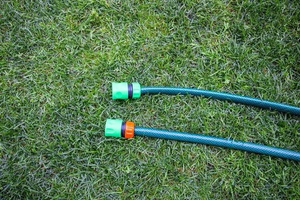 Reel of hose pipe and spraying head on grass. Flat lay.