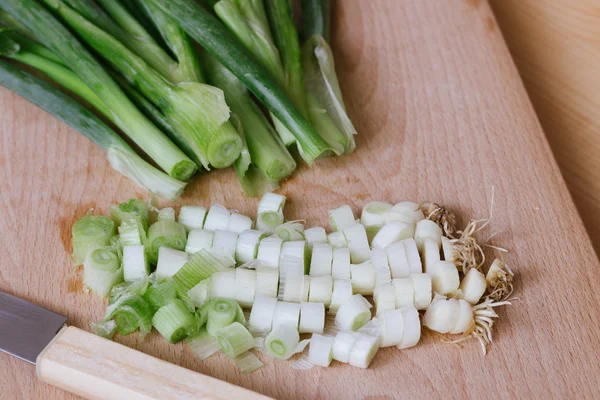Chopped green spring onions on wooden cutting board