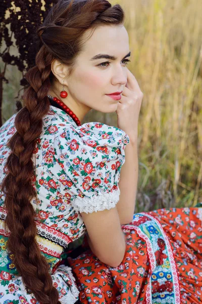 Young peasant woman, dressed in Hungarian national costume, posing over nature background