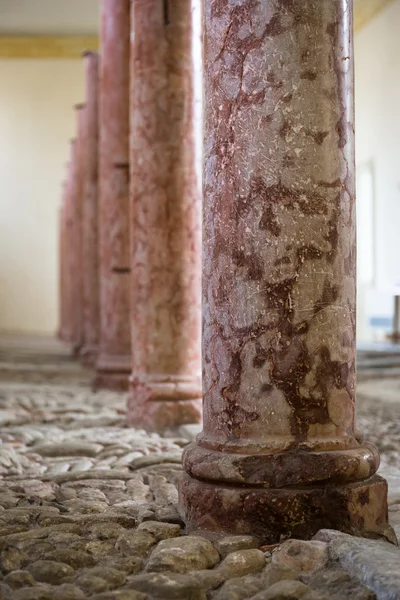 Antique marble columns resting on stone floor