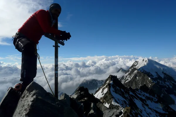 Climber posing at Lagginhorn mountain\'s summit in the Alps, Switzerland