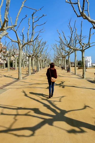 Lonely woman walking across a nice promenade on a sunny winter morning in Calella de la Costa, Maresme Seaside, Catalonia, Spain