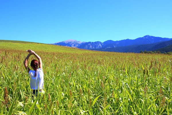 Young beautiful woman relaxing in the middle of a green cereals field during the last days of summer in the Pyrenees mountains