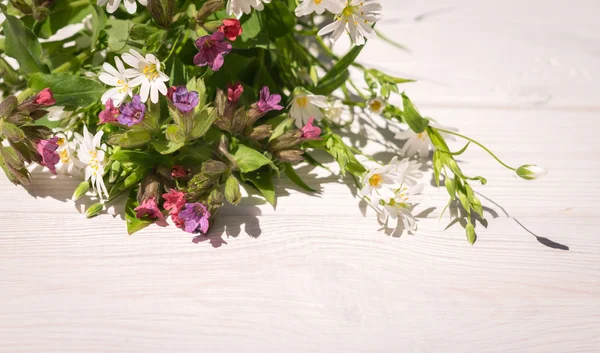In anticipation of the feast of the Trinity. Fresh field flowers and white wood background