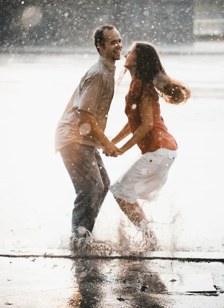 Blurry image of couple jumping under summer rain