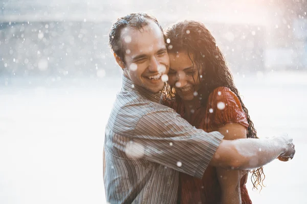 Couple in love hugging and kissing under summer rain