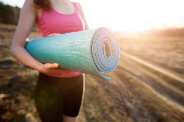 Woman walking with a yoga mat