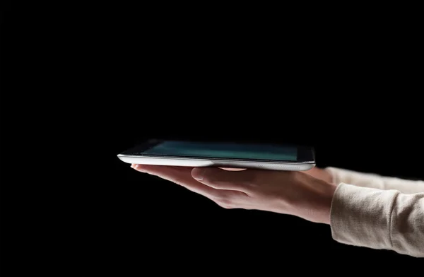 Woman hand holding digital tablet pc in the dark