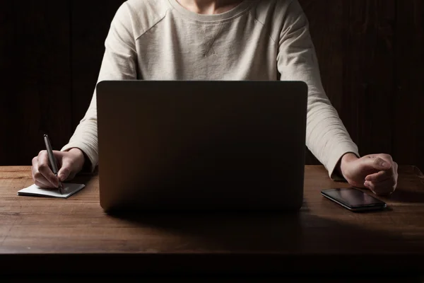 Woman hands using laptop at office desk, with copyspace in dark