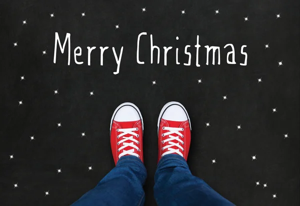 Feet wearing red shoes on black background with Merry Christmas