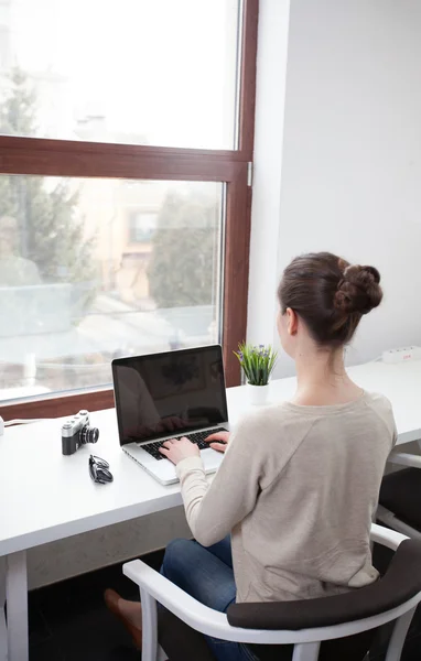 Woman using a laptop next to a window