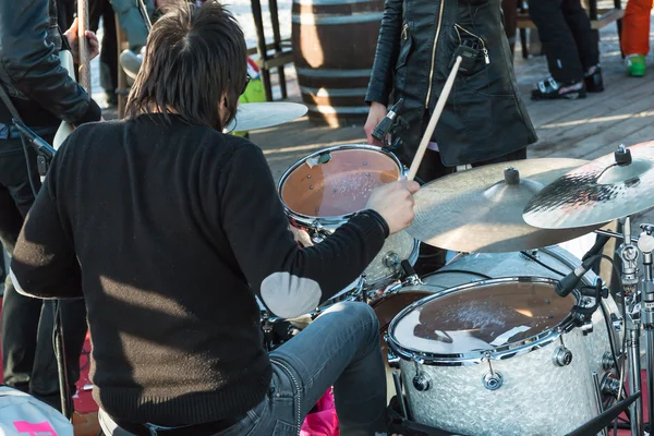 Black hair drummer during outdoor concert: rear view