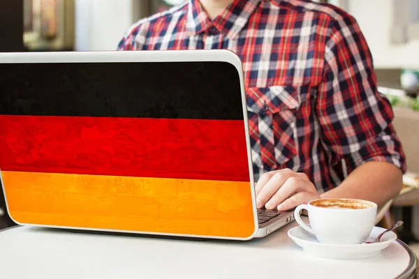 Man with cup of coffee and notebook with Germany flag