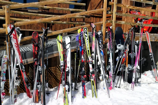 Meribel,Alps,France, March 21 2014: Varies skies and snowboards standing against an old wooden chalet bar in Three Valleys Ski Resort