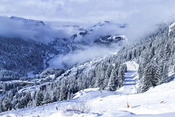 French skiing resort Flaine in Grand Massive in Alps with chalets, apartment blocks, pine forest and slopes, on a foggy winter day