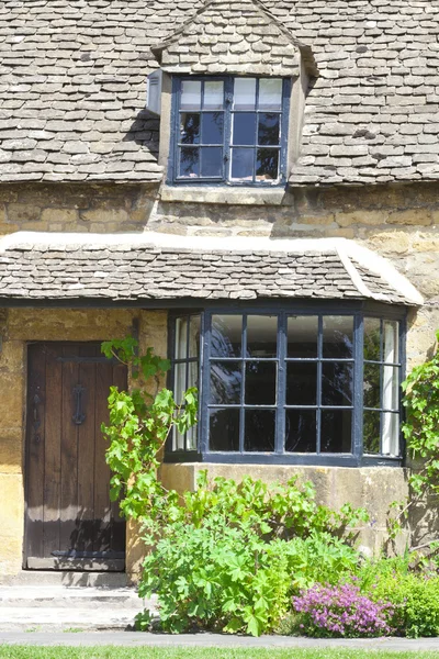 Old English cottage  surrounded by a green grape vine