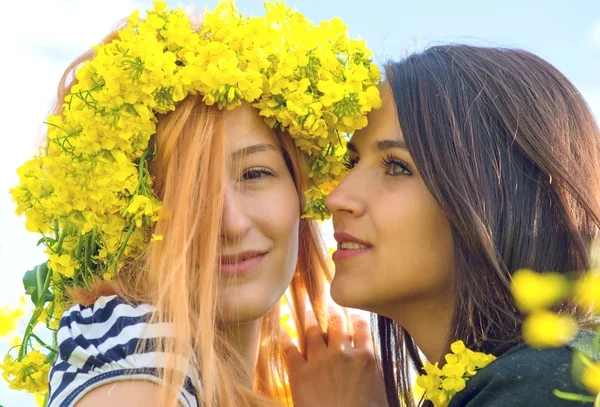 Two female best friend in a field with yellow flowers of rapeseed having fun