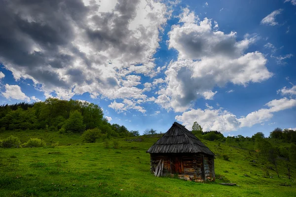 Lonely old wood house on a mountain hill against cloudy sky