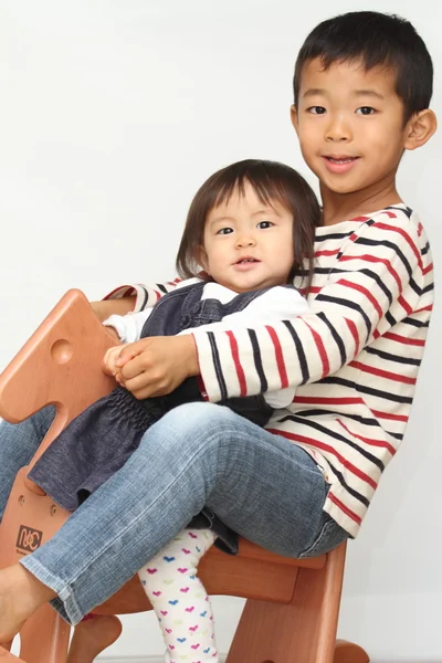 Japanese brother and sister playing with rocking horse (6 years old boy and 1 year old girl)