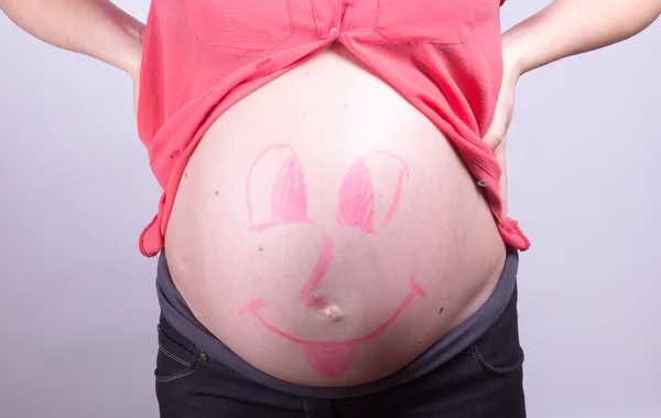 Painted  happy smiley face on the belly of pregnant girl