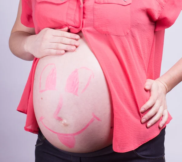 Painted  happy smiley face on the belly of pregnant girl