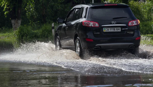 CHERKASSY, UKRAINE- JUNE 5, 2016: cars driving on a flooded road during a flood caused after heavy rain, in Cherkassy.