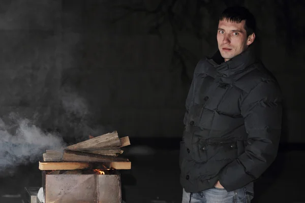 Man grilling at night with a fire thats too big.