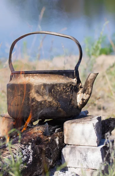 Kettle  in soot hung over the fire  on nature