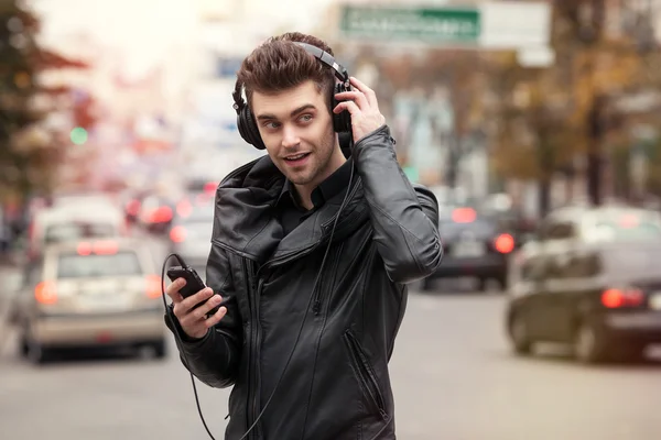 Man in headphones on the street. Standing with phone in hand