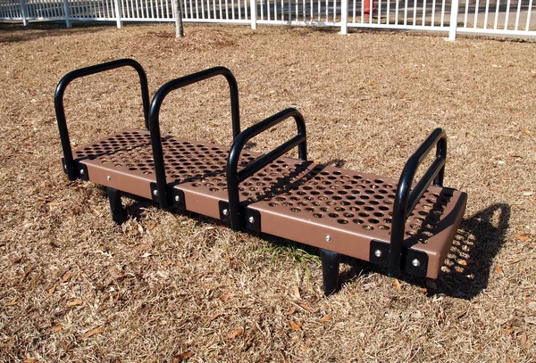 Brown and black bench dip exercise equipment in a park