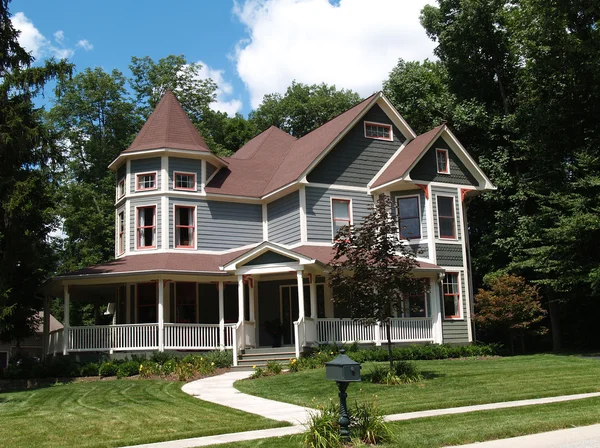 New two story Victorian residential home with vinyl or board siding on the facade styled after an old-fashioned historical house with bay windows, gingerbread and a turret.