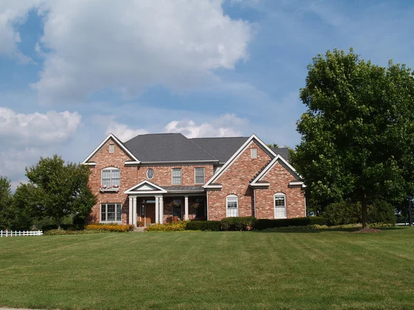 Two story large brick residential home with flower box.