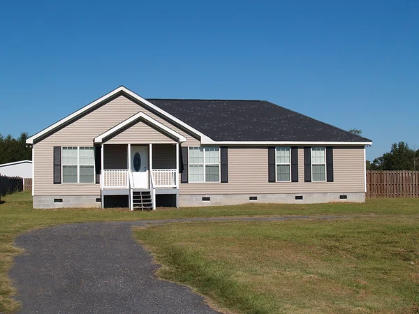 Small low income manufactured home with a covered porch and vinyl siding.