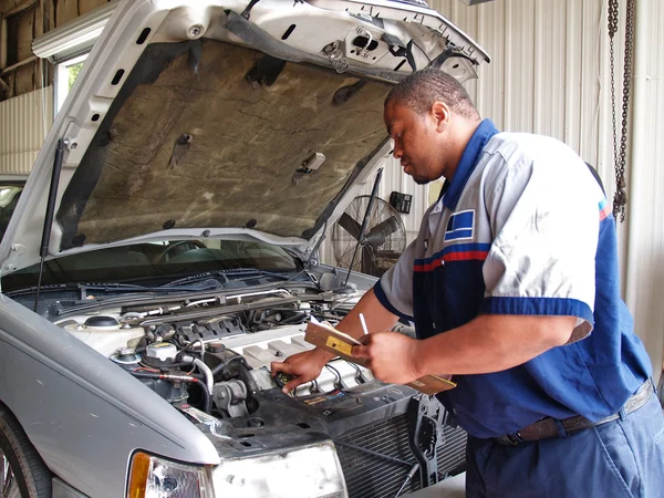 Auto mechanic checking radiator levels while performing a routine service inspection in a service garage.