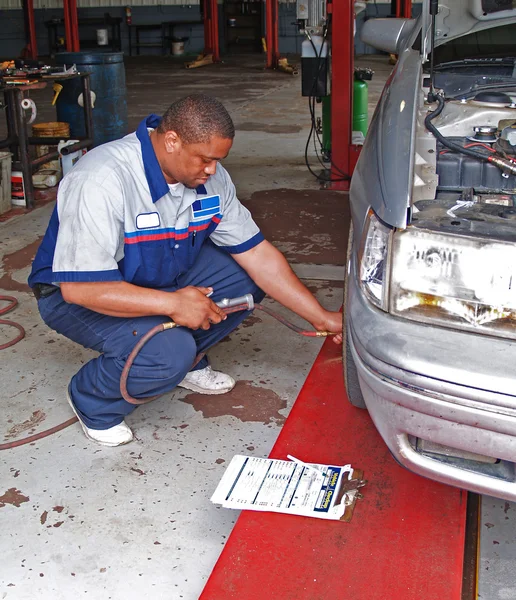 Auto mechanic inspecting a cars tire pressure in a service garage.