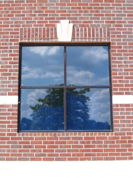 Four paned window on a red brick wall with special brickwork around it.