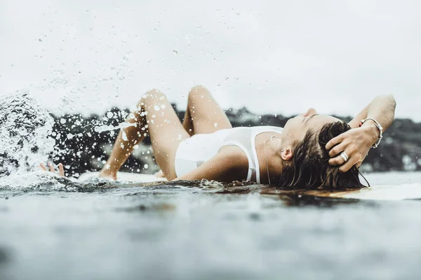 Beautiful girl in the ocean Surf in the rain