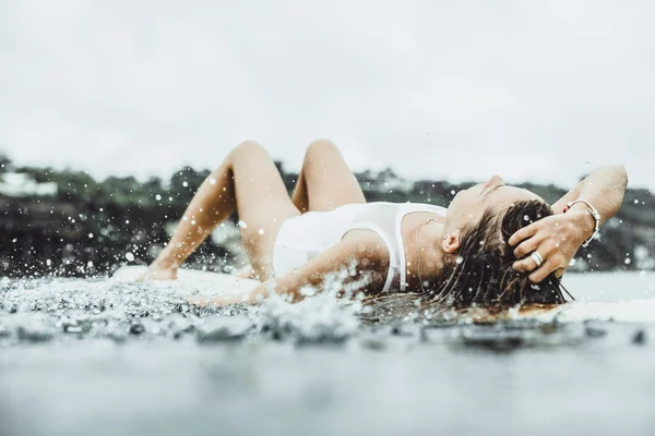Beautiful girl in the ocean Surf in the rain